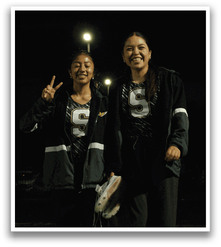 Two girls are standing in a field at night, posing for a picture. Contenido generado con IA