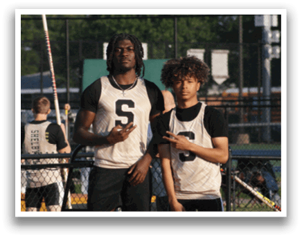 Two men in black and white uniforms are standing on a track field. Contenido generado con IA