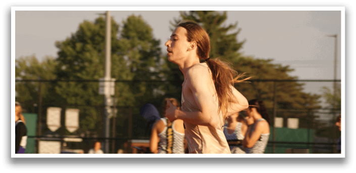 A man with long hair is running on a track while other people watch. Contenido generado con IA