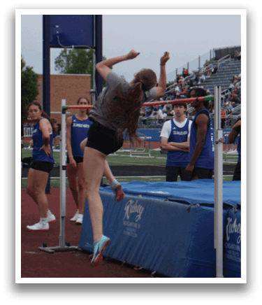 A woman is jumping over a barrier on a track, with several people watching her. Contenido generado con IA