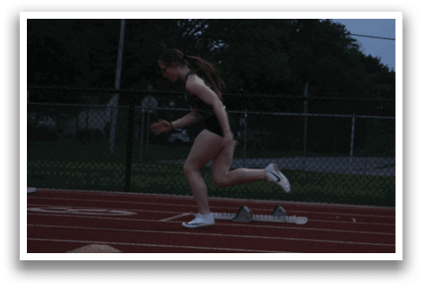 A woman is running on a track, wearing a black shirt and white shoes. Contenido generado con IA