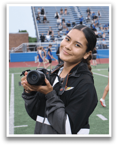 A woman is holding a camera and smiling. Contenido generado con IA