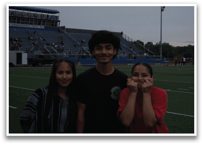 Three people pose for a photo on a football field. Contenido generado con IA