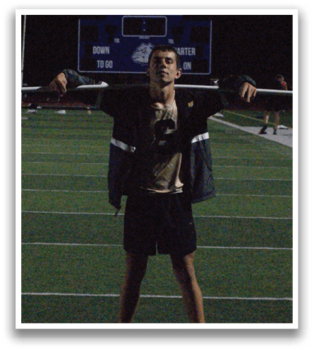 A man stands on a football field with his arms raised. Contenido generado con IA