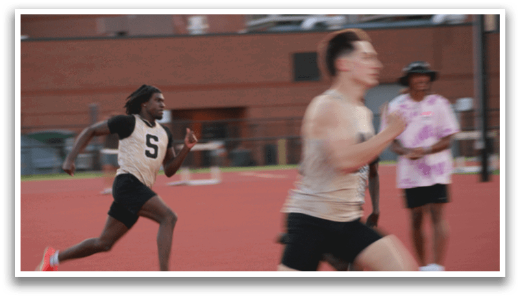 Two men are running on a track, one wearing a black shirt and the other wearing a white shirt. Contenido generado con IA