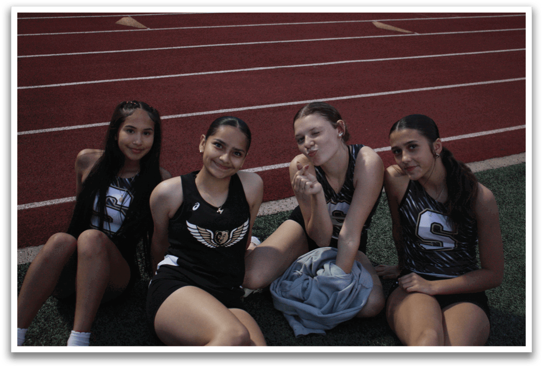 Four female athletes are sitting on the grass, posing for a picture. Contenido generado con IA