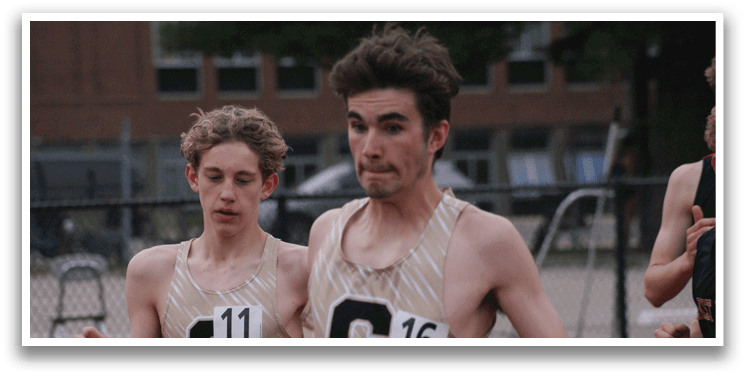 Two young men wearing gold shirts and running on a track. Contenido generado con IA
