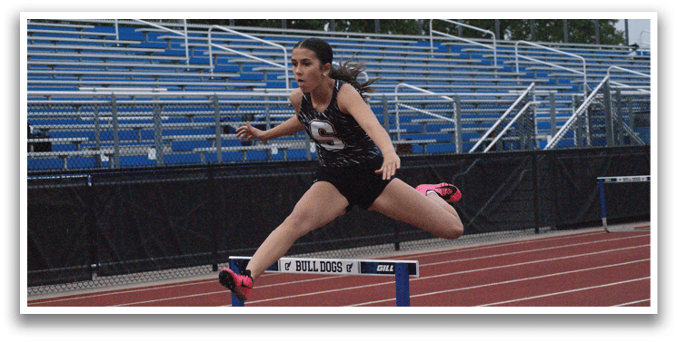 A female athlete jumps over a hurdle on a track. Contenido generado con IA