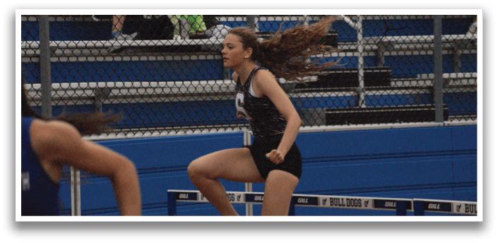 A female athlete is running on a track, with her hair flying in the wind. She is wearing a black and white outfit and is in the middle of a race. Contenido generado con IA