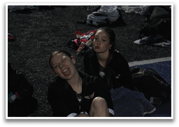 Two women sitting on the ground, one with her mouth open, the other with a ponytail. Contenido generado con IA