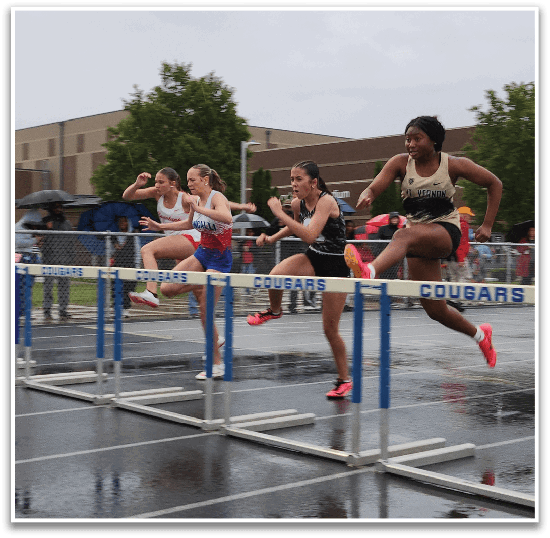 A group of women are running on a track, with one of them jumping over a hurdle. Contenido generado con IA