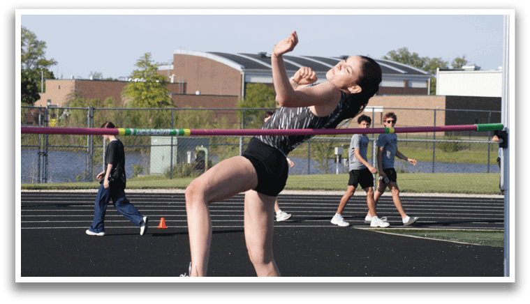 A woman is jumping in the air on a track, attempting to clear a hurdle. Contenido generado con IA
