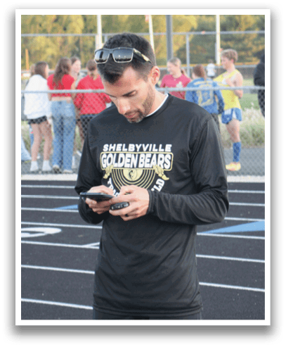 A man wearing a black shirt and shorts is looking at his cell phone. Contenido generado con IA