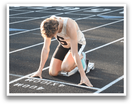 A runner is kneeling on the track, possibly preparing to start a race or taking a break. Contenido generado con IA