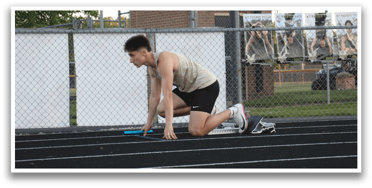 A man is bent over on a track, holding a baton in his hand. Contenido generado con IA
