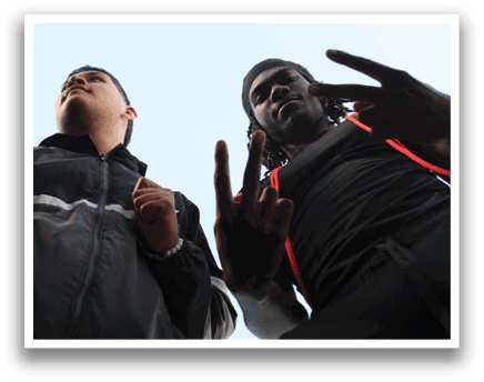 Two men are standing next to each other, one of them is wearing a black hat and the other is wearing a black shirt. They are both making the peace sign gesture. Contenido generado con IA