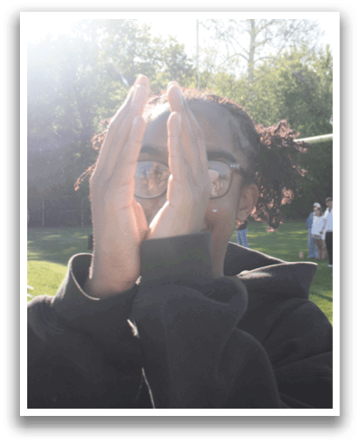 A person wearing sunglasses and a black hoodie is raising their hands in the air. Contenido generado con IA
