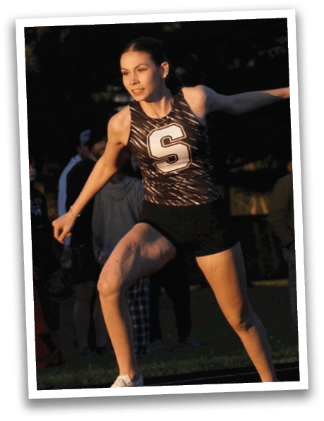 A woman wearing a black and white track suit is running on a track. Contenido generado con IA