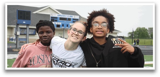 Three people pose for a picture on a field. Contenido generado con IA