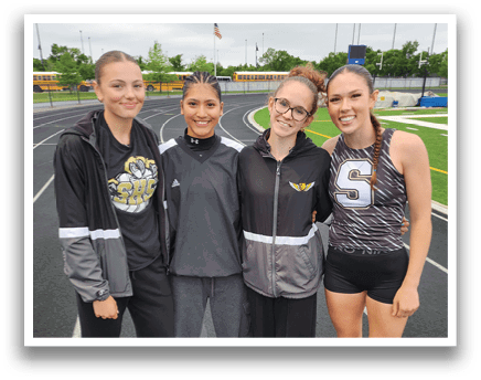 Four women pose for a picture on a track. Contenido generado con IA
