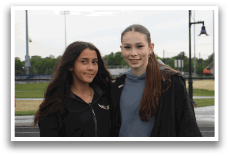 Two girls standing on a track, one is taller than the other. Contenido generado con IA