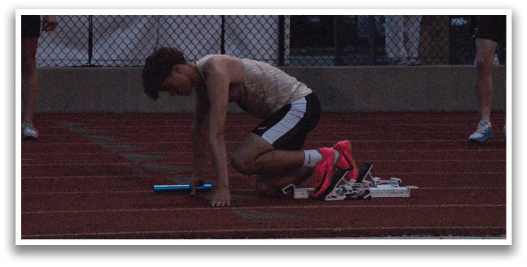 A man is bent over on a track, holding a blue object. Contenido generado con IA