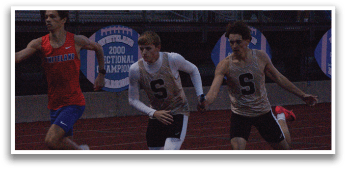 Three male runners are racing on a track. One runner is wearing a red shirt, another is wearing a white shirt, and the third is wearing a black shirt. Contenido generado con IA