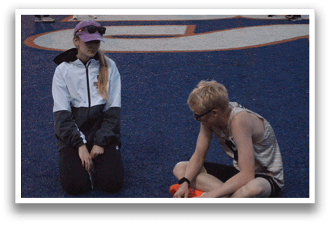 Two people sitting on a field, one with a white jacket and the other with a gold tank top. Contenido generado con IA