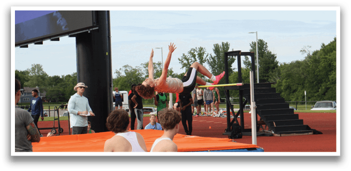 A man and woman are sitting on a bench watching a gymnast perform a trick on a bar. Contenido generado con IA