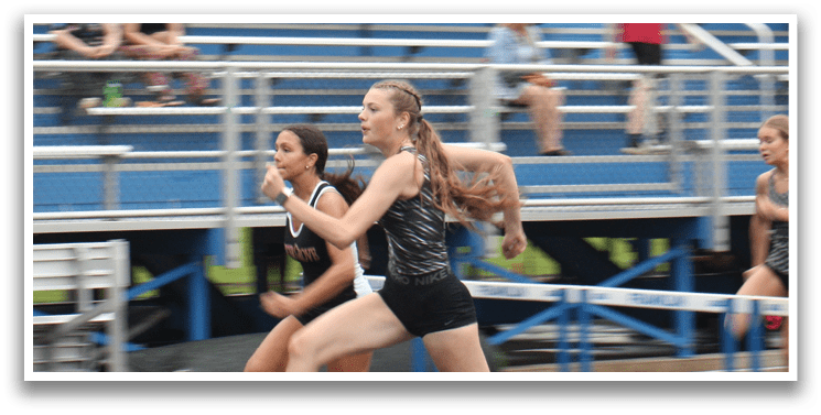 A group of girls are running on a track, with one girl in the lead. Contenido generado con IA