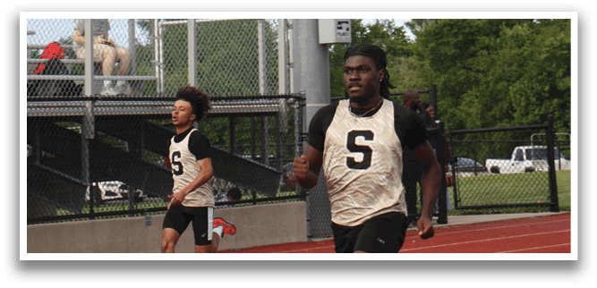 Two boys are running on a track, one wearing a number 5 jersey. Contenido generado con IA