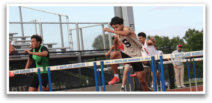 Three men are running on a track, with one of them jumping over a hurdle. Contenido generado con IA