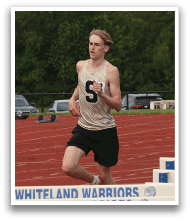 Two men are running on a track, one of them wearing a white shirt with the number 56. They are running around a set of hurdles. Contenido generado con IA