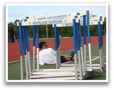 A man is sitting on a bench in a track field, wearing sunglasses. Contenido generado con IA