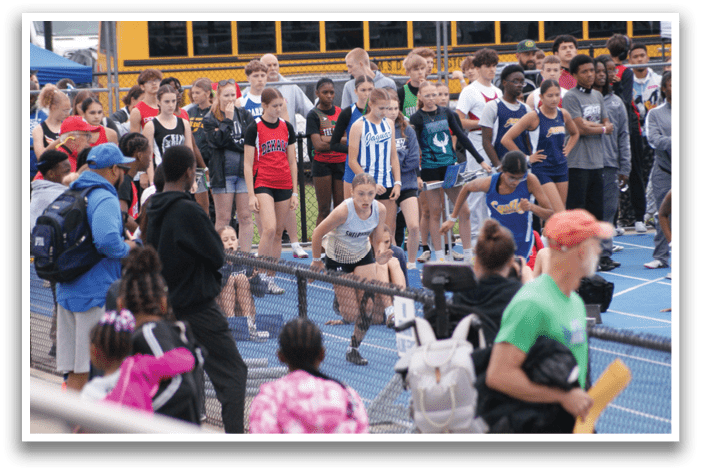 A group of people are standing on a track, watching a person run. Contenido generado con IA