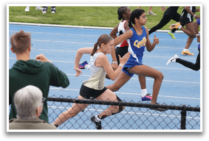 A group of people are running on a track, with one girl wearing a blue and white uniform. Contenido generado con IA