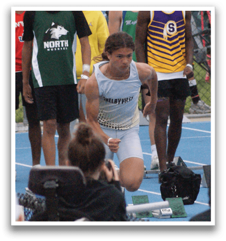 A group of people are watching a race, with some sitting on chairs and others standing. The racers are wearing uniforms and are in various positions on the track. Contenido generado con IA