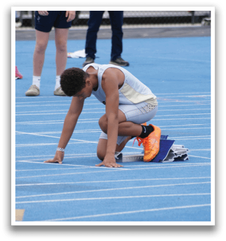 A man is kneeling on a track with his head down. Contenido generado con IA