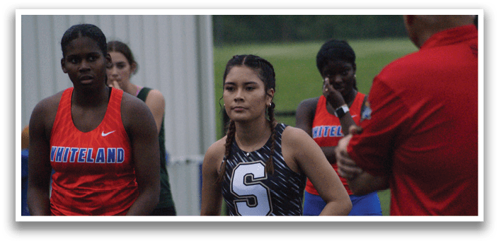 A group of female athletes wearing uniforms and standing on a track. Contenido generado con IA