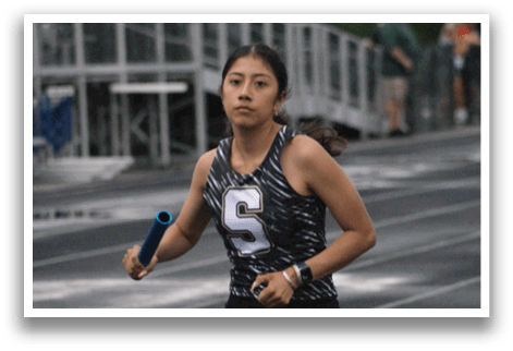 A woman wearing a black and white shirt is running on a track. Contenido generado con IA