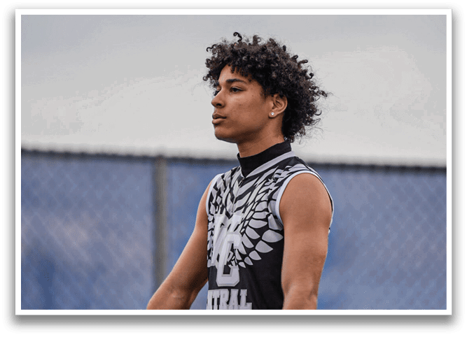 A young man with a black and white shirt holding a baseball bat. Description generated by AI