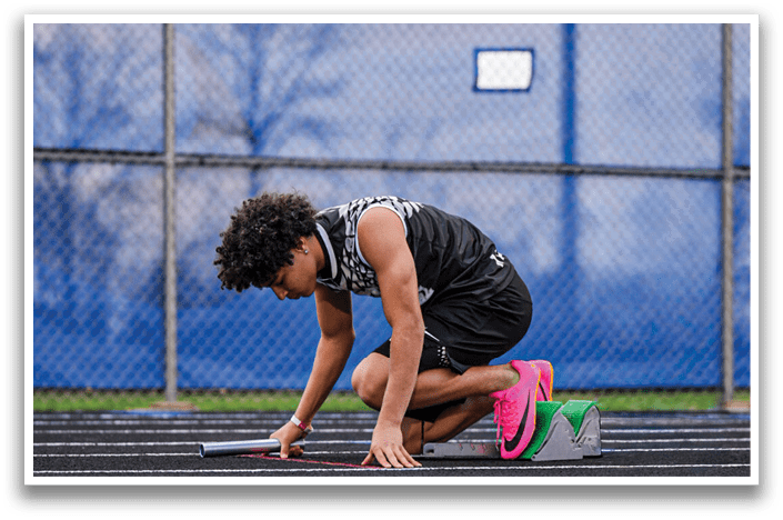 A man is bending over on a track. Description generated by AI
