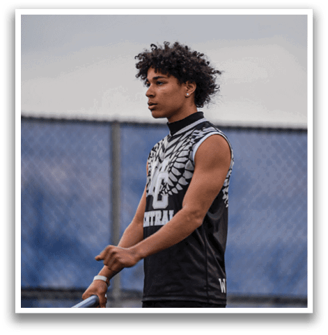 A young man wearing a black and white shirt is holding a tennis racket. Description generated by AI