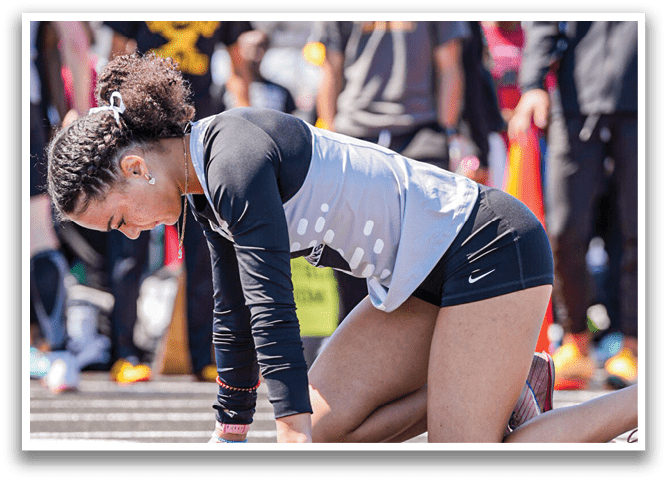 A woman is bending over on a track. Description generated by AI