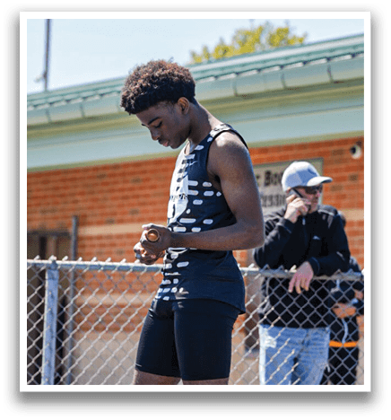 A man wearing a black track suit is standing on a track. Description generated by AI