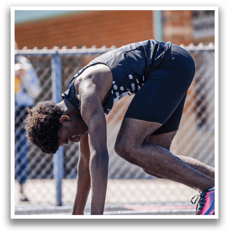A man is bending over on a track. Description generated by AI