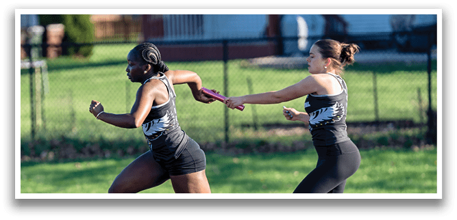 Two girls running on a track. Description generated by AI