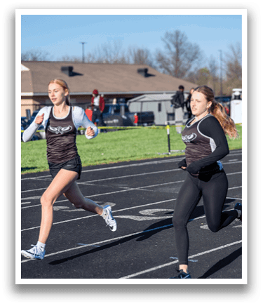 Two girls running on a track. Description generated by AI