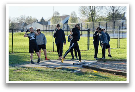 A group of people standing on a track. Description generated by AI