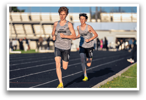 Two boys running on a track. Description generated by AI